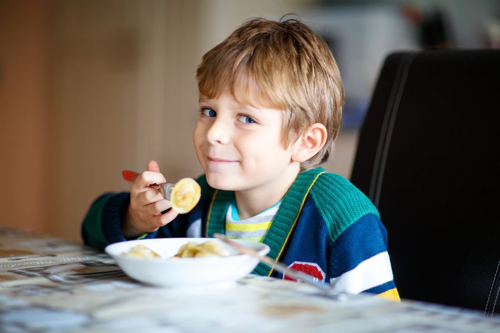 Ung pojke i förskoleåldern äter lunch på förskolan